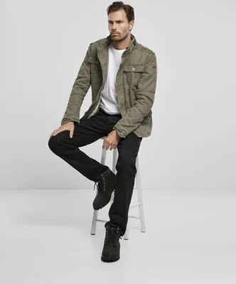 A man is sitting on a stool wearing a jacket and jeans.