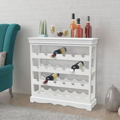 A white wine rack filled with bottles, placed in a room with a teal armchair and a brick wall.