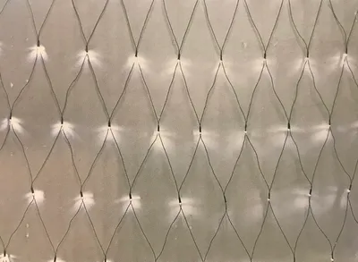 A close-up view of a net of white LED lights against a light gray background.