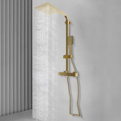 A gold shower system with a rain showerhead and handheld showerhead is mounted on a textured gray wall. Water is flowing from the rain showerhead.