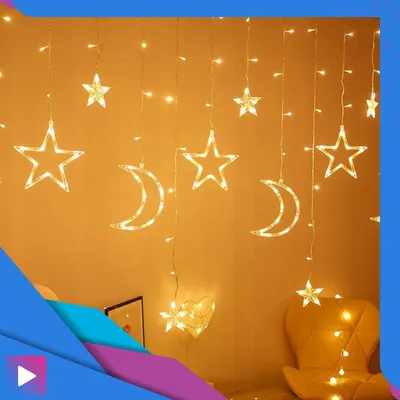 A wall decorated with string lights shaped like stars and moons, with a chair in the background.