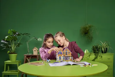 Two girls building a LEGO house on a table.