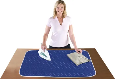 A woman is ironing clothes on a table with a portable ironing mat.