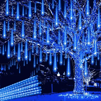 A tree decorated with blue LED meteor shower lights at night, with a pile of the lights in the foreground.