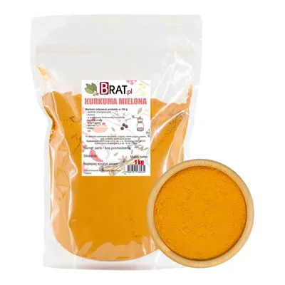 A bag of ground turmeric next to a wooden bowl filled with turmeric powder.