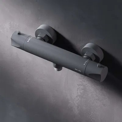 A gray shower thermostat mounted on a gray textured wall.