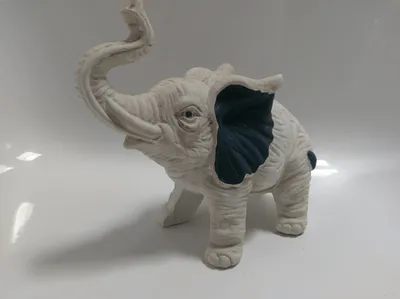 Der weiße Elefant ist in einer stehenden Position dargestellt, sein Rüssel ist hoch erhoben.