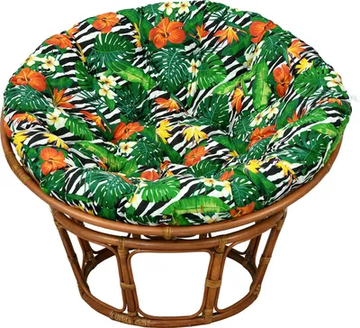 A round cushion with a tropical leaf and zebra print pattern sits on a round rattan chair.