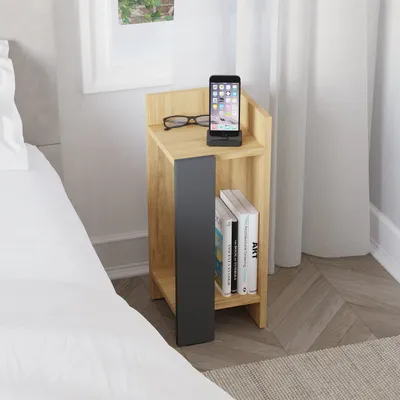 A modern bedside table next to a bed, with a phone and glasses on top.