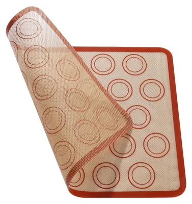 A silicone baking mat with circular guides for macarons or cookies, partially lifted.