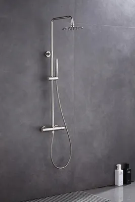 A modern shower set mounted on a gray tiled wall.