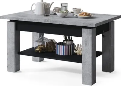 A coffee table with a concrete look top and black base, set against a white background. It is styled with a teapot, cups, and decorative items.