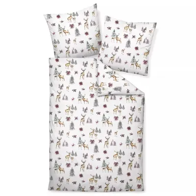 A flat lay of a duvet cover and pillowcases with a Christmas-themed pattern of deer and trees.