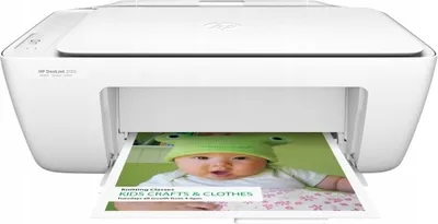 A white HP Deskjet 2130 printer is shown printing a document with a baby's face on it.