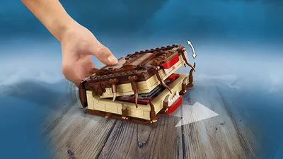 A hand is shown opening a LEGO Harry Potter Monster Book of Monsters.
