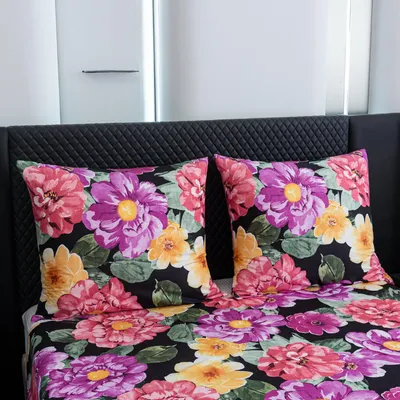 A close-up view of a bed with floral patterned bedding and two pillows.