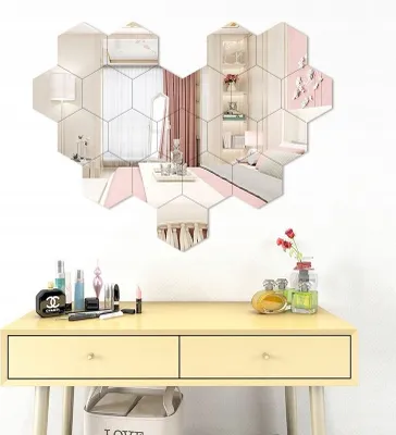 A vanity table with makeup and perfume, with a wall decorated with hexagonal mirrors.
