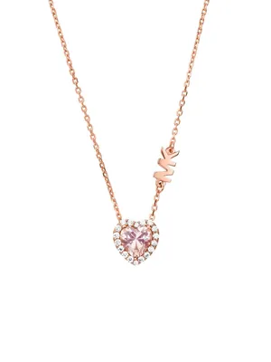 A rose gold necklace with a heart-shaped pink pendant surrounded by clear stones and the MK logo.
