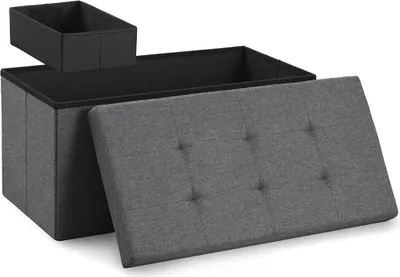 A gray storage ottoman with its lid open, revealing a black interior and a smaller black storage box inside.