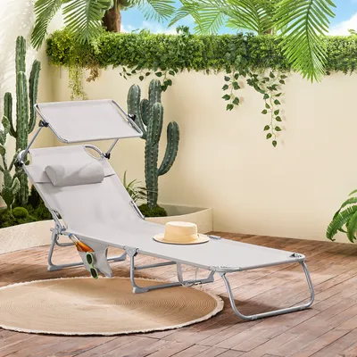 A beige sun lounger with a canopy and pillow is set up on a wooden deck, surrounded by potted plants and cacti, creating a relaxed outdoor oasis.
