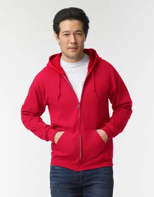 A man wearing a red zip-up hoodie and blue jeans, posing against a white background.