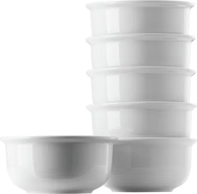 A stack of white dessert bowls and one bowl in front.