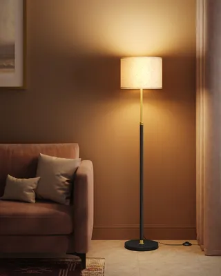 A floor lamp is placed next to a sofa in a living room.