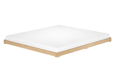 A white mattress on a low wooden bed frame against a white background.