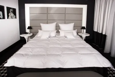 A neatly made bed with white bedding and pillows in a modern bedroom setting.