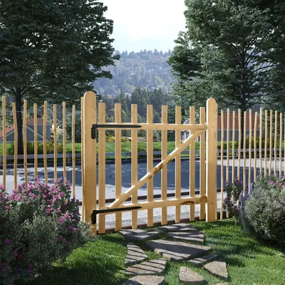 A wooden garden gate and fence in a natural outdoor setting with trees and a hilly landscape in the background.
