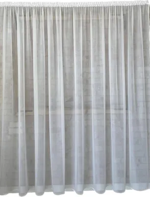 A white sheer curtain hanging against a brick wall.