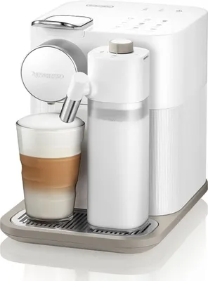 A white De'Longhi Nespresso coffee machine with a glass of latte macchiato and a milk frother.