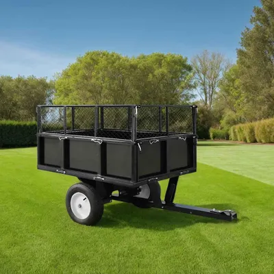 A black utility trailer is parked on a green lawn with trees and a blue sky in the background.