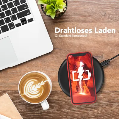 A desk scene with a laptop, coffee, and a smartphone charging wirelessly.