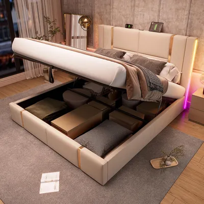 A modern bedroom with a beige upholstered storage bed with the mattress lifted to reveal storage space underneath. The bed has LED lighting along the headboard and sides.