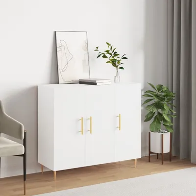 A white sideboard with gold handles is shown in a room with a chair and a plant.