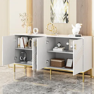 A white sideboard with gold legs and handles, open to reveal shelves with books and decorative items.