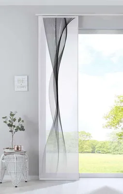 A panel curtain with a black wavy pattern is shown hanging in front of a window with a view of trees and grass.