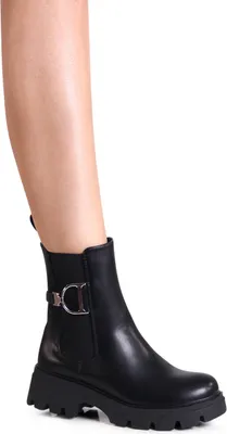 A person's leg wearing a black boot.