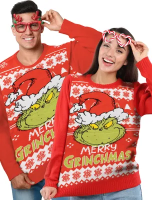 A man and a woman wearing matching Grinch-themed Christmas sweaters.
