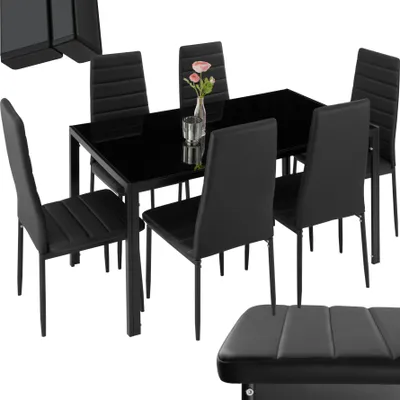 A black dining table with six black chairs and a vase with flowers on the table.