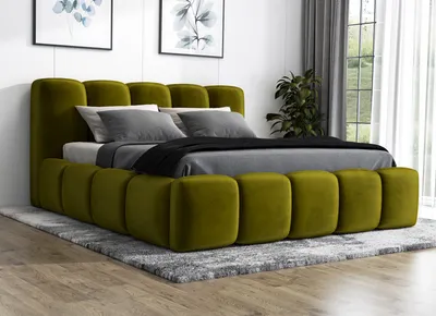 A modern green upholstered bed with a mattress and pillows, placed on a gray rug in a room with artwork on the wall and a window with curtains in the background.