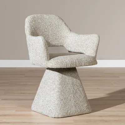 A single swivel chair with a textured taupe fabric and a geometric base, shown in a studio setting with a light gray wall and wooden floor.