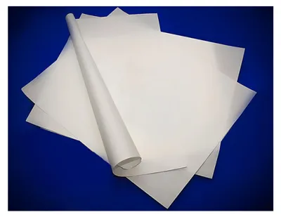 Several sheets of white paper are stacked, with one sheet rolled into a tube.