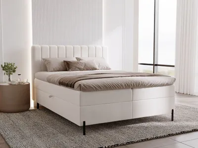 A cream-colored bed with pillows and a duvet in a minimalist bedroom.