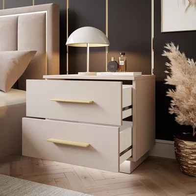 A bedside table with two drawers, a lamp, and decorative items.