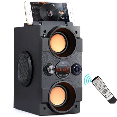 A black Bluetooth speaker with a smartphone docked on top, and a remote control with signal waves emanating from it.