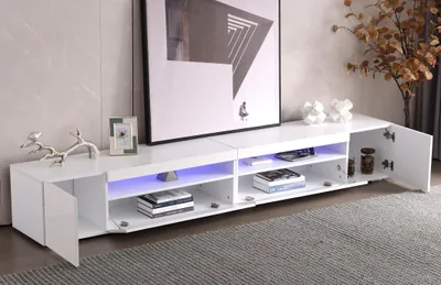 A white TV stand with open cabinets and shelves, some with blue LED lighting, in a living room setting.