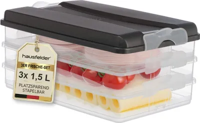 A stack of three clear food storage containers with a black lid, filled with food items like tomatoes and cheese, and a product tag hanging from the lid.