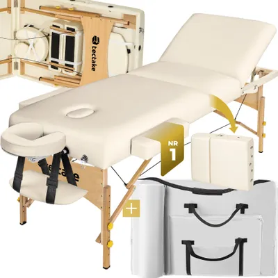 A cream-colored massage table with wooden legs and accessories, presented in a studio setting.